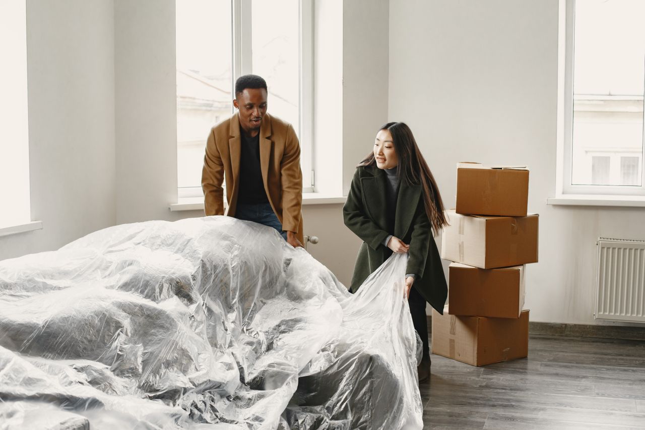 Crafting Captivating Headlines: Your awesome post title goes here A couple unpacking and setting up their new home with a covered couch and boxes.
